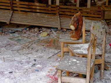 Görüntü, sandalyede oyuncak ayı olan ihmal edilmiş bir odayı gösteriyor. Sandalyede kirli pelüş oyuncak. Pripyat 'ta terk edilmiş bir anaokulunda başsız bir oyuncak ayı..