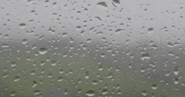 Yağmurlu bir gün manzaralı, penceredeki yağmur damlalarının videosu. pano