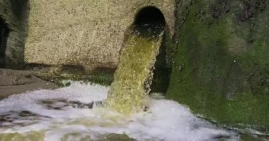 Kaya duvarındaki bir boru su boşaltarak küçük bir şelale oluşturuyor. Ağır çekim. pano