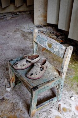 Yıpranmış bir odada, üzerinde eski bir çift ayakkabı olan eski bir sandalye..