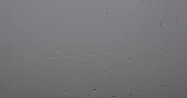 Penceredeki bulanık arkaplanlı yağmur damlalarının videosu.