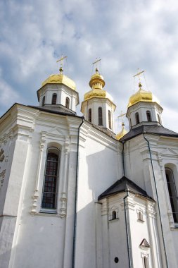 Bu pitoresk anda, Catherine 'in Kilisesi, muhteşem beyaz dış görünüşü ve altın kubbeleriyle, yumuşak, dalgalı bulutları olan mavi gökyüzünün arka planına karşı sahne alır..