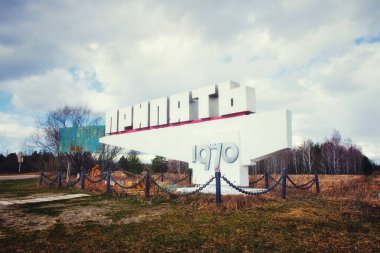 İhmalkarlığın izlerini ve zamanın akışını taşıyan terk edilmiş bir yapı. Kiril alfabesi ile metin: Pripyat, şehrin adı.