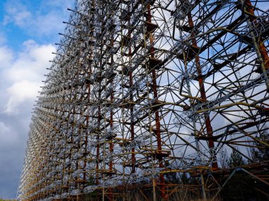 Paslı metal kuleler sayısız kabloyla sarmalanmış. Duga, ICBM fırlatmaları için bir erken tespit sistemi için ufukta görünen bir Sovyet radar istasyonu..
