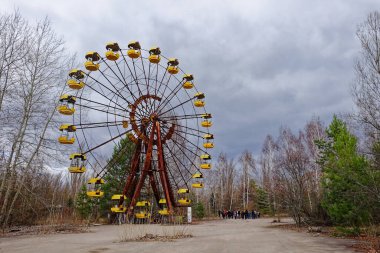 Sarı gondollu eski bir dönme dolap yapraksız ağaçlarla çevrilidir..