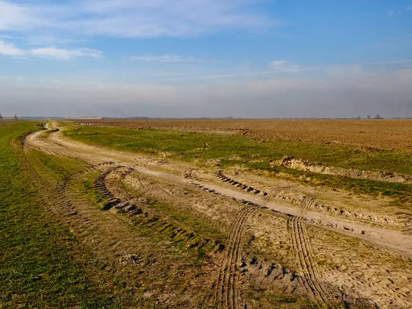 Görüntü huzurlu kırsal bir ortam yakalıyor. Tarlalar ve dolambaçlı bir yol var..