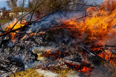 Küçük bir ateş küllerin ve dumanların arasında yanar.