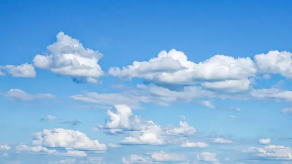 Durgun mavi bir gökyüzü beyaz bulutlarla benekli.