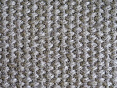 Bir sürü deseni olan tüylü gri bir kumaşın yakın çekimi. Kumaş bir döngü ve düğüm deseni oluşturacak şekilde örülmüş. Sahne rahat ve sıcak..