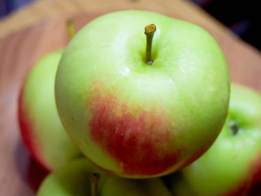 Taze yeşil elmalar. Tahta masada kırmızı allık sürmüş çıtır elmalar..