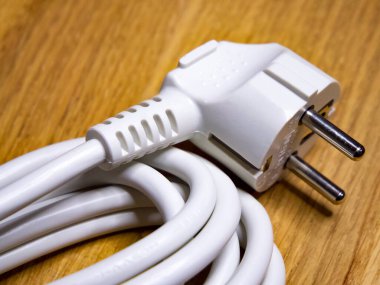 Nizhyn, Ukrayna, 25 Eylül 2021. Tahta bir yüzeye sarılı iki çatallı bir elektrik kablosu elektronik cihazlar için kullanıldığını gösteriyor. İllüstrasyon Editörü.