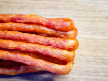 Tahta bir masanın üzerinde bir sürü et parçası var. Çubuklar uzun ve ince ve hepsi aynı renk. Çubuklar sıraya dizildi ve yenmeye hazır görünüyorlar..