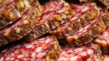 Salam yakın plan. Bir yığın ince dilimlenmiş salam, görünür yağ ve et mermeriyle, mutfak temaları için ideal..