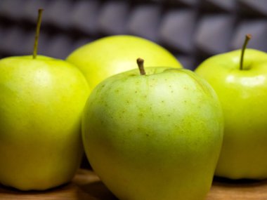 Taze yeşil elmalar, ahşap yüzey, sağlık odaklı görüntü..