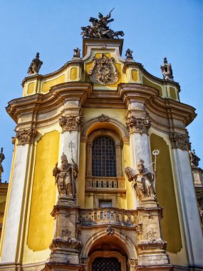 Barok Kilisesi Cephesi: Açık mavi gökyüzünün altında tarihi mimariyi yansıtan süslü heykellerle süslenmiş bir barok kilise cephesi. Lviv şehrindeki St. George Katedrali