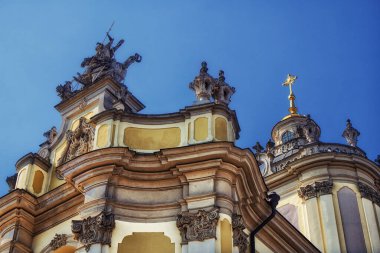 Mimari Majesteleri: Güneşli bir gökyüzünün altında heykeli ve altın haçı olan bir barok bina, tarihi bir ihtişam sergiliyor. Lviv şehrindeki St. George Katedrali.