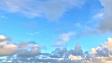 Bulutlar, güneş ışığı, mavi gökyüzü; sakin ruh hali, doğa temalı tasarımlar için uygun.