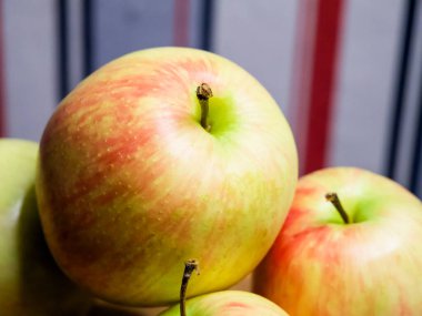 Canlı Elma Detayları. Ön planda, doğal sağlığı temsil eden, bulanık elmalarla çevrili, dokulu bir teni olan renkli bir elma..
