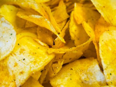 Baharatlı cips yığını. Bir yığın altın patates cipsi, otlarla tatlandırılmış..