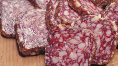 Tahta ince dilimlenmiş salam sunar, mermer zenginliğinin tadını davet eder..