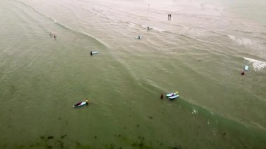 West Cork, İrlanda, 3 Temmuz 2022. Bir grup birey sudaki sörf tahtalarına yerleştirildi. Dalgaları bekliyor gibi görünüyorlar. Su çok sakin. Acemi sörfçüler. Denizdeki sörfçüler.