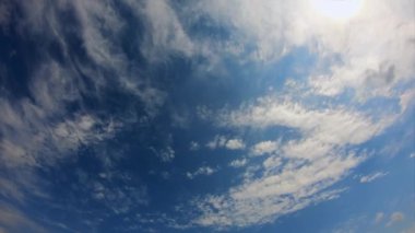 Video geniş bir mavi gökyüzü gösteriyor. Birçok beyaz bulut var, bazıları ince ve diğerleri daha yoğun, gökyüzüne yayılmış. Görüntü iyi aydınlatılmış, muhtemelen güneş tarafından..