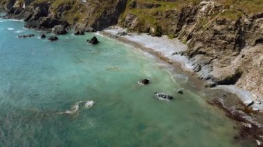 Rocky Shoreline manzaralı sakin sahil plajı. Berrak turkuaz suların kayalık oluşumlara ve çakıllı kıyılara çarptığı sakin bir sahil manzarası..