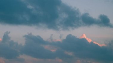 Beyaz bulutlar, açık mavi gökyüzü ile çelişen videoda kümelenmiştir. Büyük, koyu gri bir bulut.