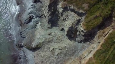 Kıyı şeridi yeşil bitki örtüsü ve gri kayaların karışımı ve canlı bir kontrast sunuyor. Hem sakin hem de engebeli doğal bir manzara..