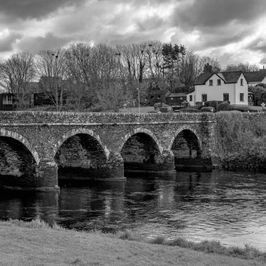 Kemerleri olan taş bir köprü nehri boydan boya geçerek evi olan küçük bir köye gider. Ilen Nehri üzerindeki Köprü. Skibbereen yakınlarında, County Cork, İrlanda..