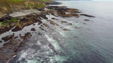 Kayalık bir sahil manzarası, kayalık bir sahili, küçük bir sahili ve çekilen bir gelgiti gösteriyor..