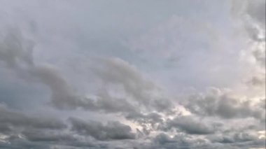 Beyaz ve gri bulutların şekil ve büyüklükleriyle bulutlu bir gökyüzü. Bulutlar çoğunlukla orta zeminde, bazıları ön plana doğru uzanıyor gibi görünüyor..