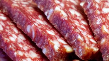 İnce dilimlenmiş salamın yakın çekimi. Video birkaç ince salam diliminin yakın çekimini gösteriyor. Belirgin dokusunu ve rengini gösteriyor..