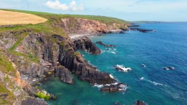 Coastal Cliffs 'de. Engebeli uçurumların panoramik manzarası berrak turkuaz sulara sahip engin bir okyanusa bakıyor..