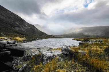Sabahın erken saatlerinde sisli tepelerin arasına yerleşmiş sakin bir göl ortaya çıkar. Kayalık kıyı yemyeşil ile zıt düşerek, huzurlu doğal bir ortam yaratıyor..