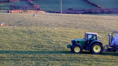 West Cork, 1 Kasım 2024. Büyük gümüş tanklı bir traktör çimenli bir arazide ilerliyor. Traktör bir tarım operasyonunun parçası ve tank gübre yaymak için kullanılıyor..