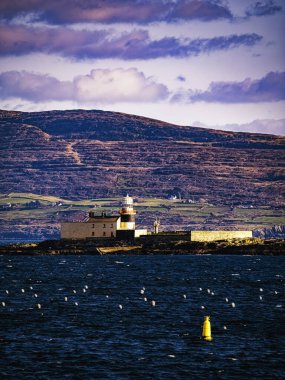 Kırmızı çatılı beyaz bir deniz feneri mavi suyla çevrili küçük bir adada yer almaktadır. Ada karanlık kayalarla kaplı..