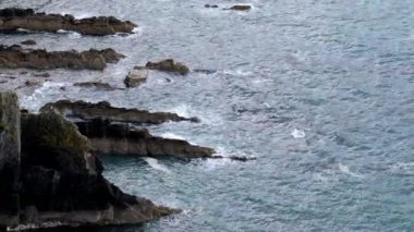 Dalgalar, doğanın gücünü açığa çıkaran bir kıyı bölgesinin kayalık kayalıklarına çarpar. Sabahın erken saatlerinde okyanus kıyıya ulaştığında manzaraya sakinleştirici bir hava katar..