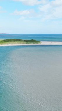 Sakin bir sahil manzarasının havadan görüntüsü. İnce, beyaz bir kum yığını denize düşüyor..