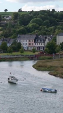 Parlak gökyüzünün altında yemyeşil yemyeşil manzaralı bir sahil kasabasında tekne.