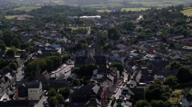 Gri çatılı birçok ev yeşil ağaçların arasında bir araya toplanmış, büyük bir kilise merkezi bir özelliktir..