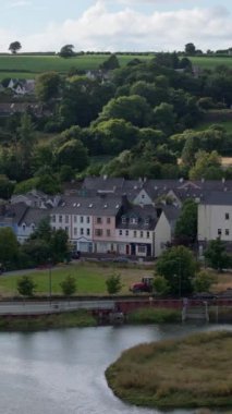 Bir kasabanın genel görünüşü, evleri, yolları ve nehri gösteriyor. Manzara kırsal ve kentsel özelliklerin bir karışımıdır..