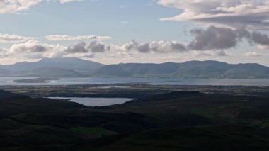 Nefes kesici manzara bulutlu bir gökyüzünün altında yuvarlanan tepeler ve görkemli dağlar arasında yuva yapmış sakin bir gölü gösteriyor. Sakin sular doğal güzelliği yansıtır..