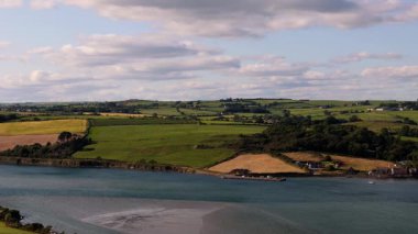 Yuvarlanan tepeler ve canlı tarlalar huzurlu körfez boyunca uzanıyor, sakin kırsal bir ortamda doğanın güzelliğini gözler önüne seriyor..