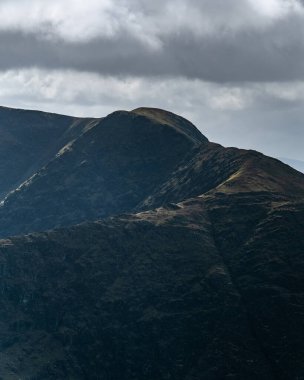 yemyeşil tepeler dramatik bir şekilde bulutlu bir gökyüzüne yükselir. Gün batımının sıcak renklerinde yıkanırlar. Aşağıdaki sakin vadide keşif ve macera bekliyor..