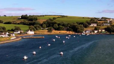 Birkaç beyaz ev bir körfezin kıyısında yer almaktadır. Su çok sakin. Küçük tekneler demirliyor. Toprak usulca yuvarlanıyor, yeşil tepeler.