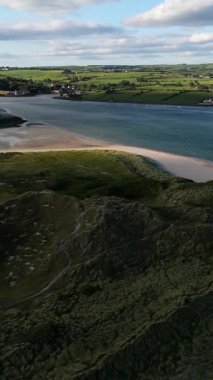 Altın saat boyunca İrlanda 'daki sakin körfezin ve yemyeşil tarlaların güzel kıyı manzarası.