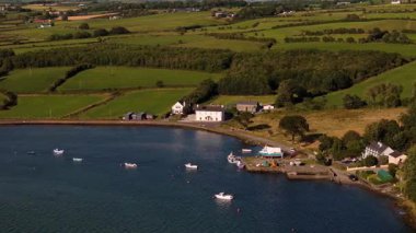 Huzurlu bir sahil köyünde huzurlu bir körfez boyunca antika evler ve renkli tekneler sergileniyor. Çevresini saran yemyeşil tepeler, doğanın alacakaranlıktaki güzelliğini vurguluyor..