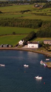 Altın saat boyunca sakin bir körfezde tekneleri ve yemyeşil yeşillikleri olan sahil köyü.