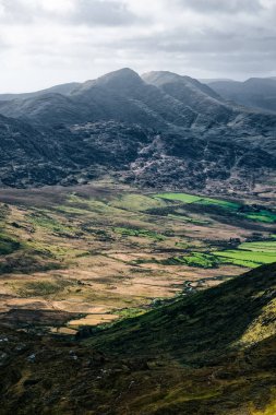 Carrauntoohil geçidinin çarpıcı manzarası tepeler ve yemyeşil alanlar ile dramatik bir gökyüzü altında İrlanda 'da.